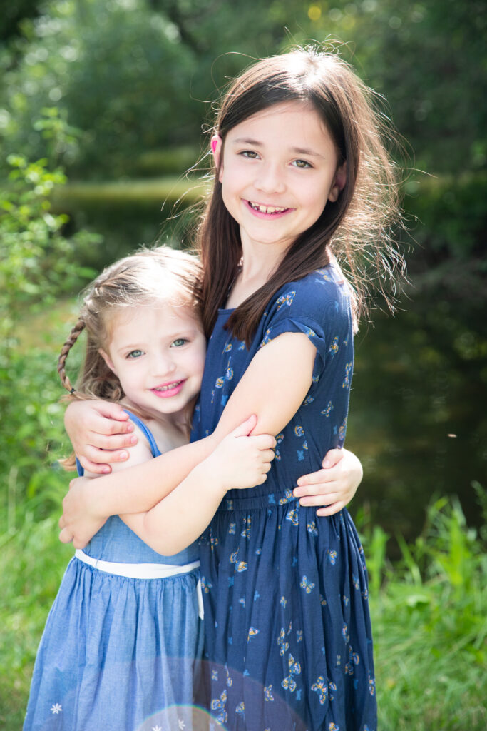 Sisters hug and look at camera at Mill Pond Park in Saline Michigan