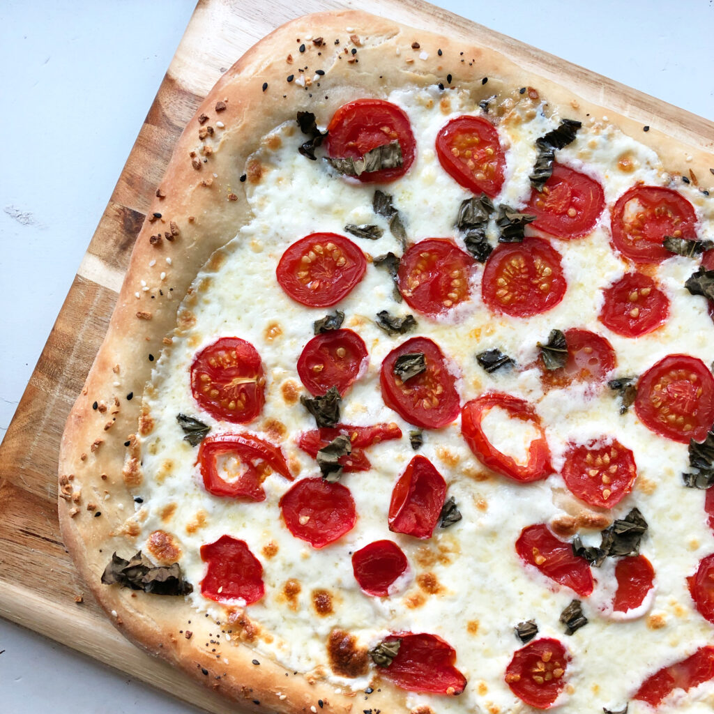 homemade margarita pizza on wooden cutting board