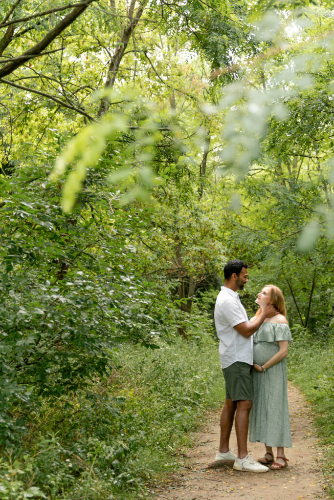 Soon to be father and mother stand on path at Saginaw Forest in Ann Arbor Michigan and cuddle during maternity photo session