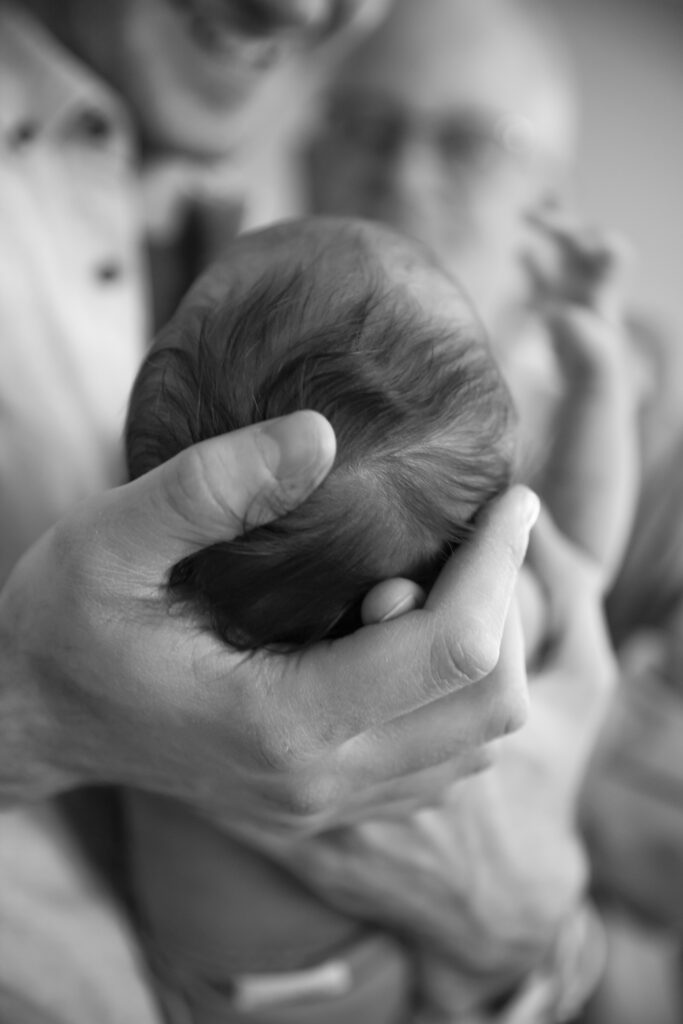 black and white photo of father cradling newborn daughter's head