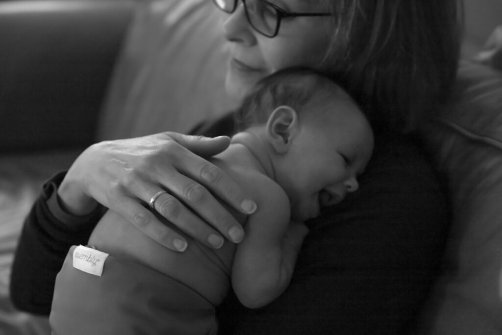 black and white photo of grandmother cuddling with newborn baby