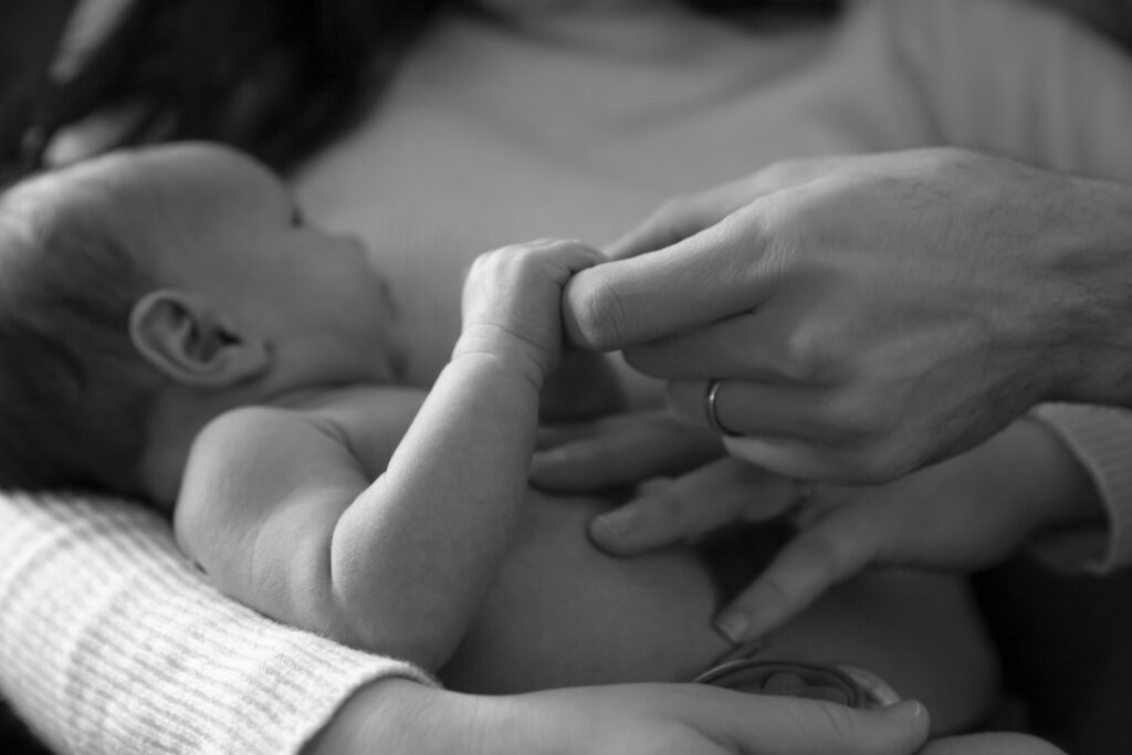 black and white photo close up of father holding newborn daughter's hand