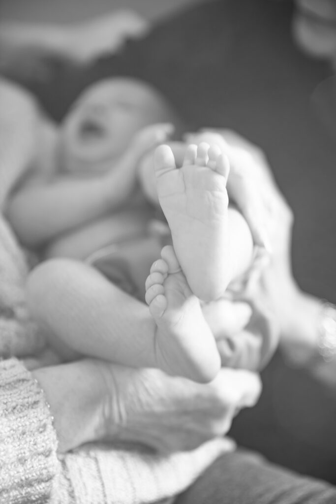 black and white photo close up of newborn baby's feet in the air