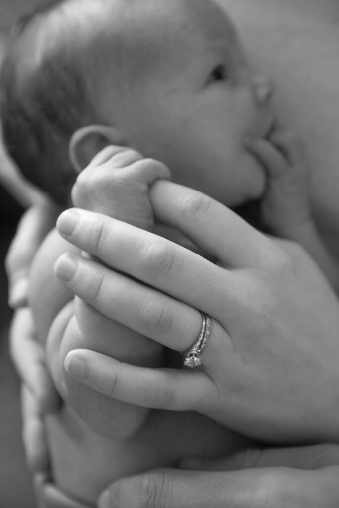 black and white photo close up of newborn holding mother's finger