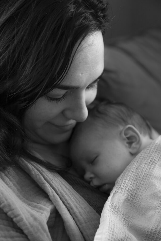 black and white photo close up of mother holding newborn baby sleeping on her chest