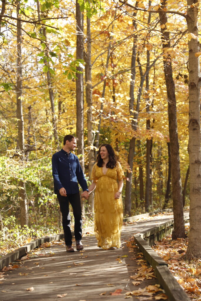 Raw photo of couple walking along boardwalk in woods in the fall among bright yellow trees at parker mill county park in ann arbor michigan