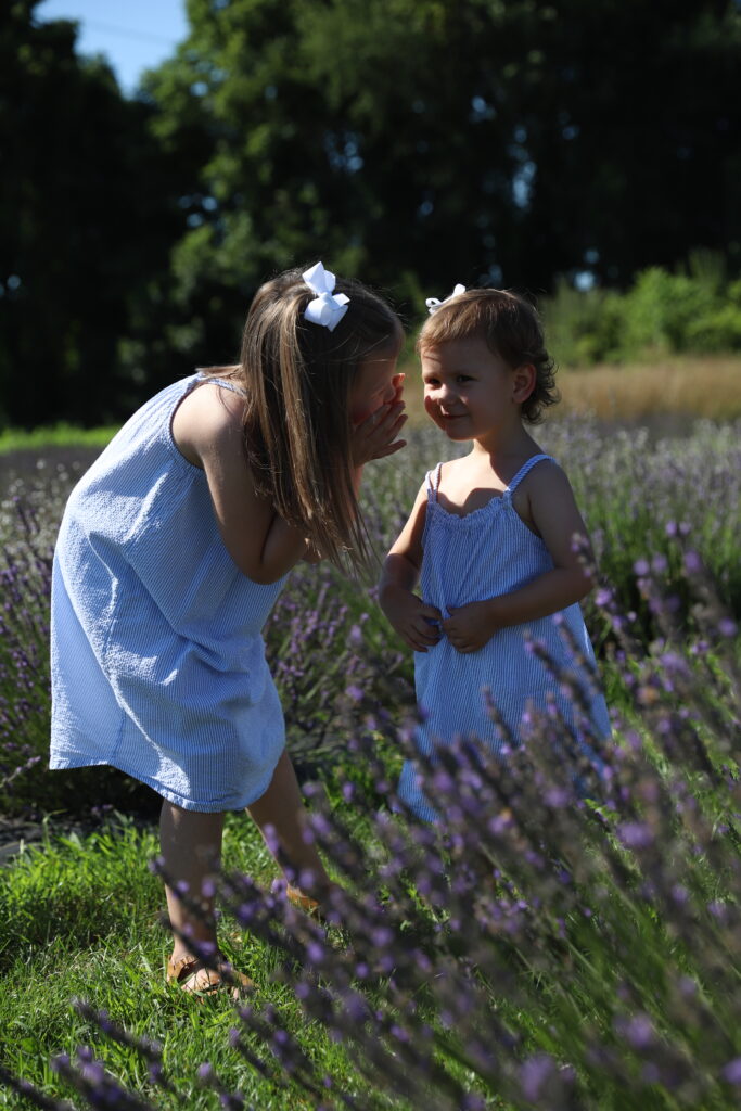 raw photo of sisters whispering to each other in a lavender field