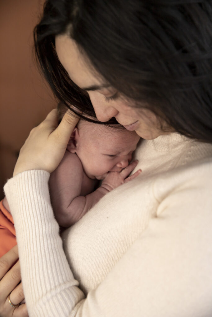 close up of mother holding newborn baby cuddling on her chest