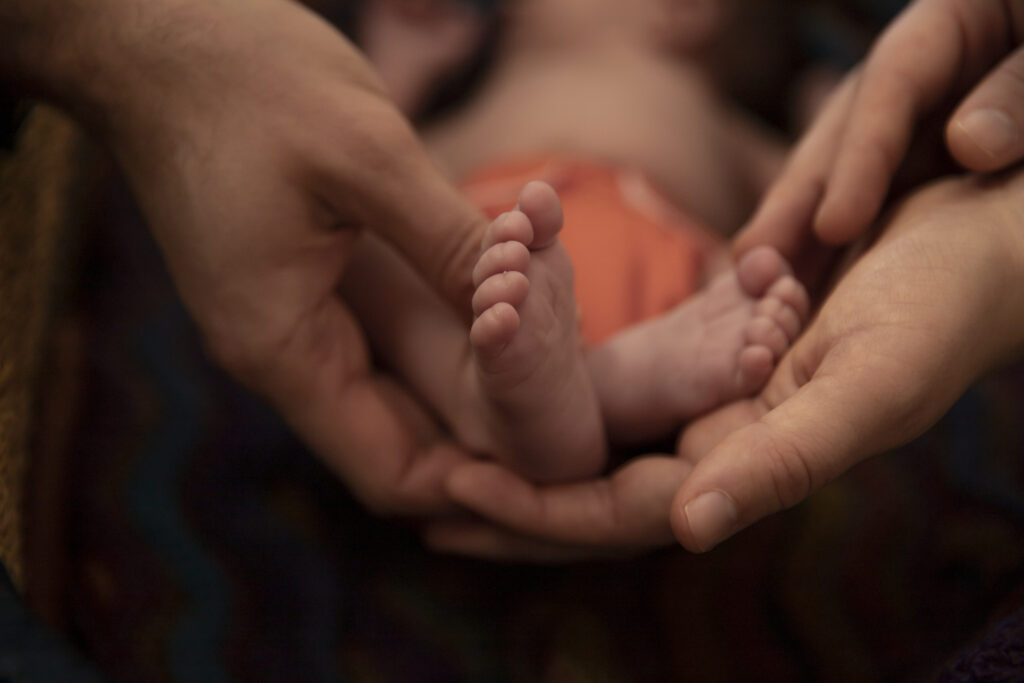 close up of mother and father cupping newborn baby's feet