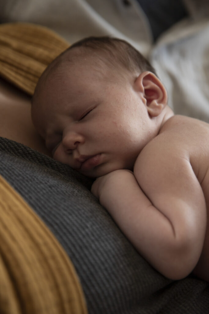 close up of newborn baby sleeping on mother's chest