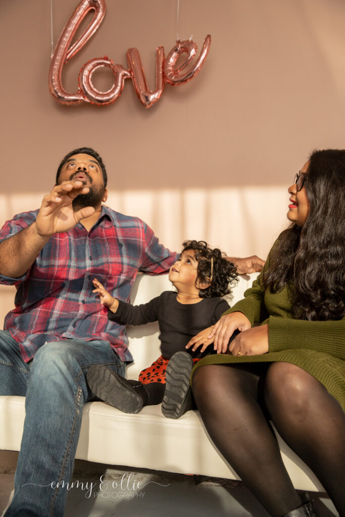 toddler girl and parents look up at balloon out of frame and smile