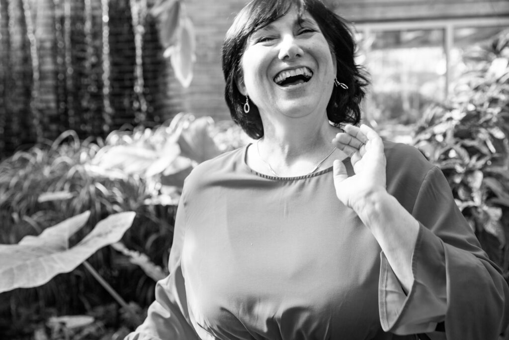 Black and white image of woman laughing in matthaei botanical gardens conservatory in ann arbor michigan