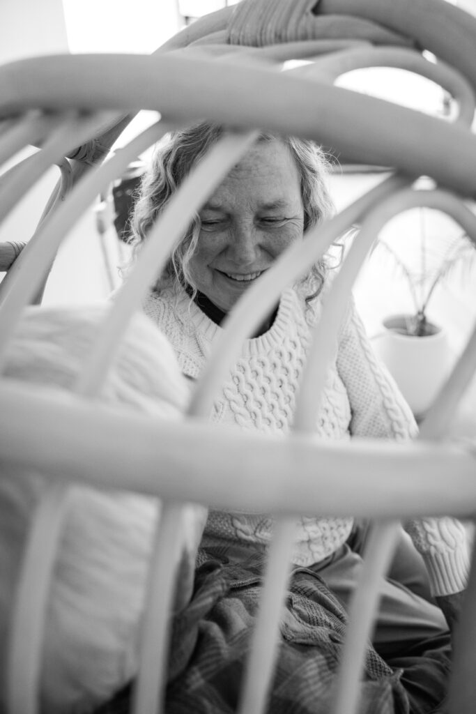 black and white image of grandparents looking at each other through gaps in rattan bowl chair at studiostudio in ann arbor michigan