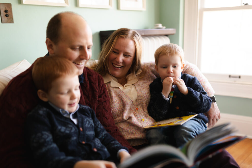 family of four reads together on a big chair in reading nook