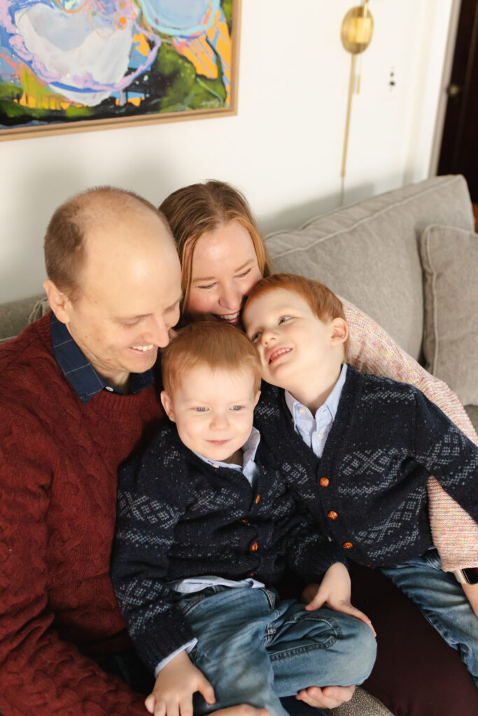 family of four sits on couch and cuddles