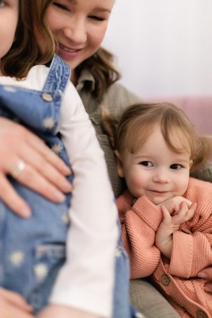 toddler girl cuddles into mom and big sister at studiostudio in ann arbor michigan