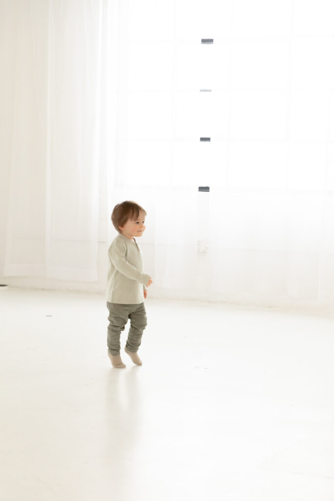 toddler runs on tip toes through bright white room at studiostudio in ann arbor michigan