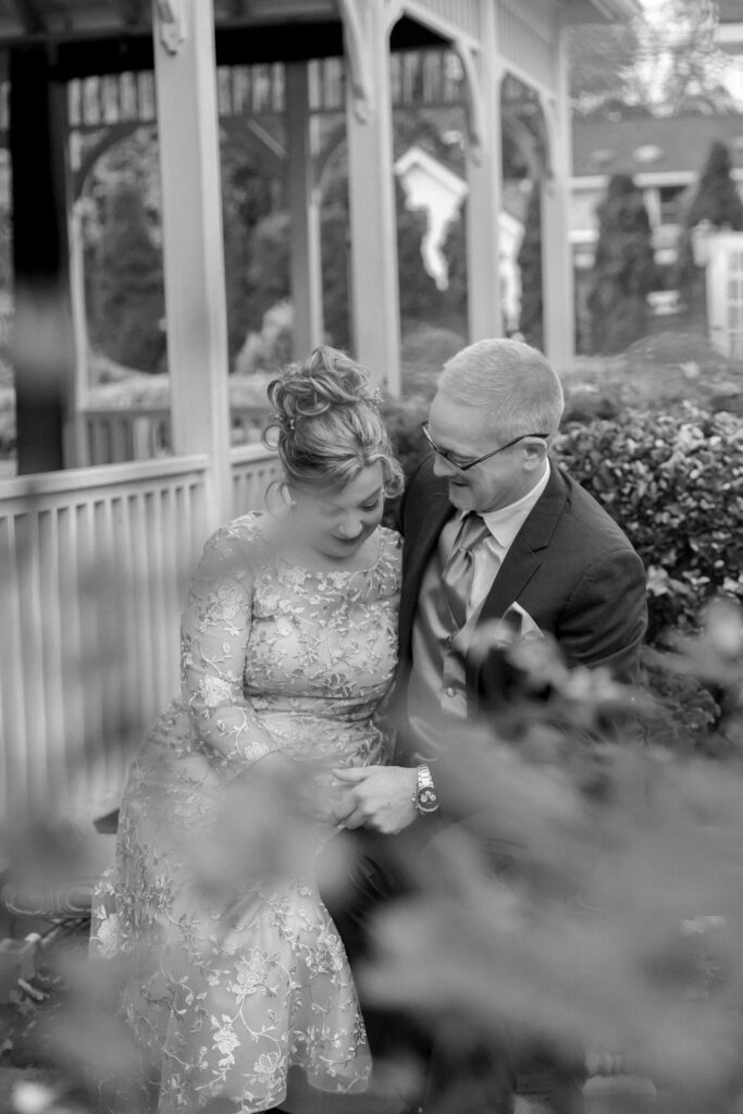 black and white photo of couple sitting near outdoor pavilion during wedding