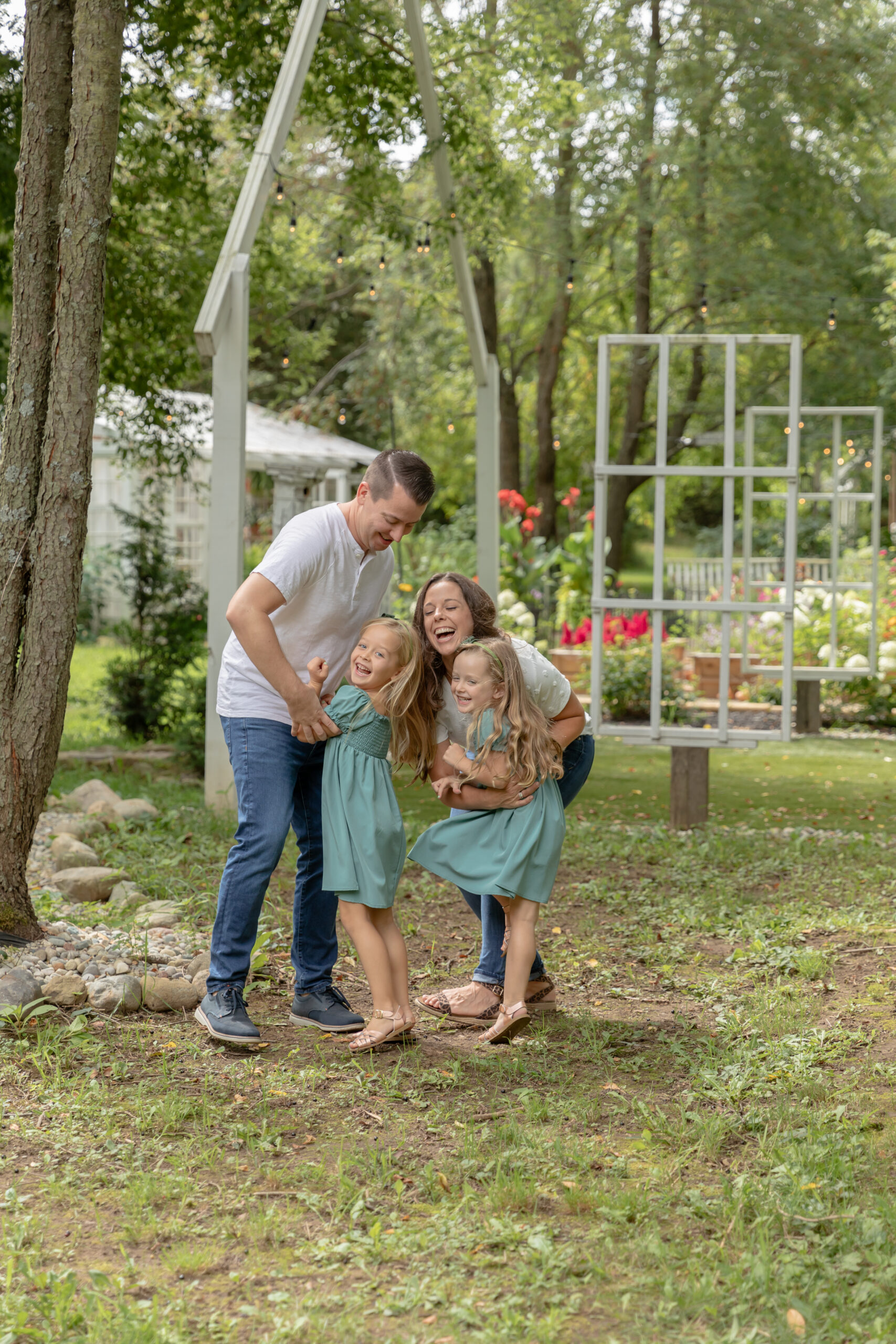 Family of four laughs together in a garden at Rustic Wild Arrow in Brooklyn, Michigan