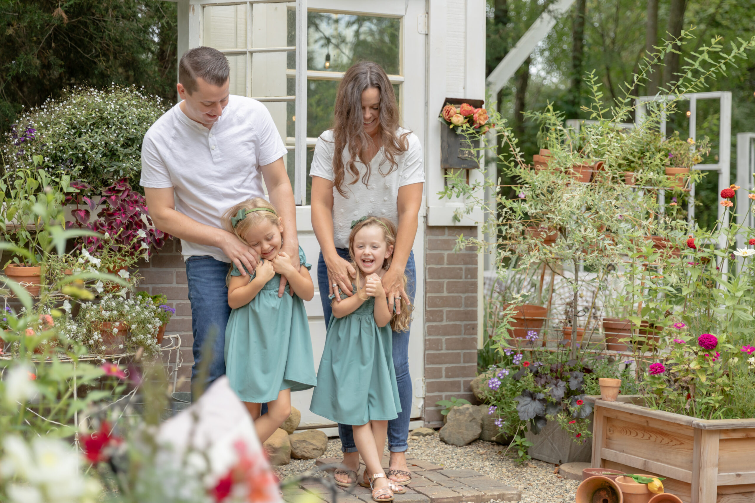 Family of four stands in front of a flower stand facade surrounded by flowers at Rustic Wild Arrow in Brooklyn, Michigan