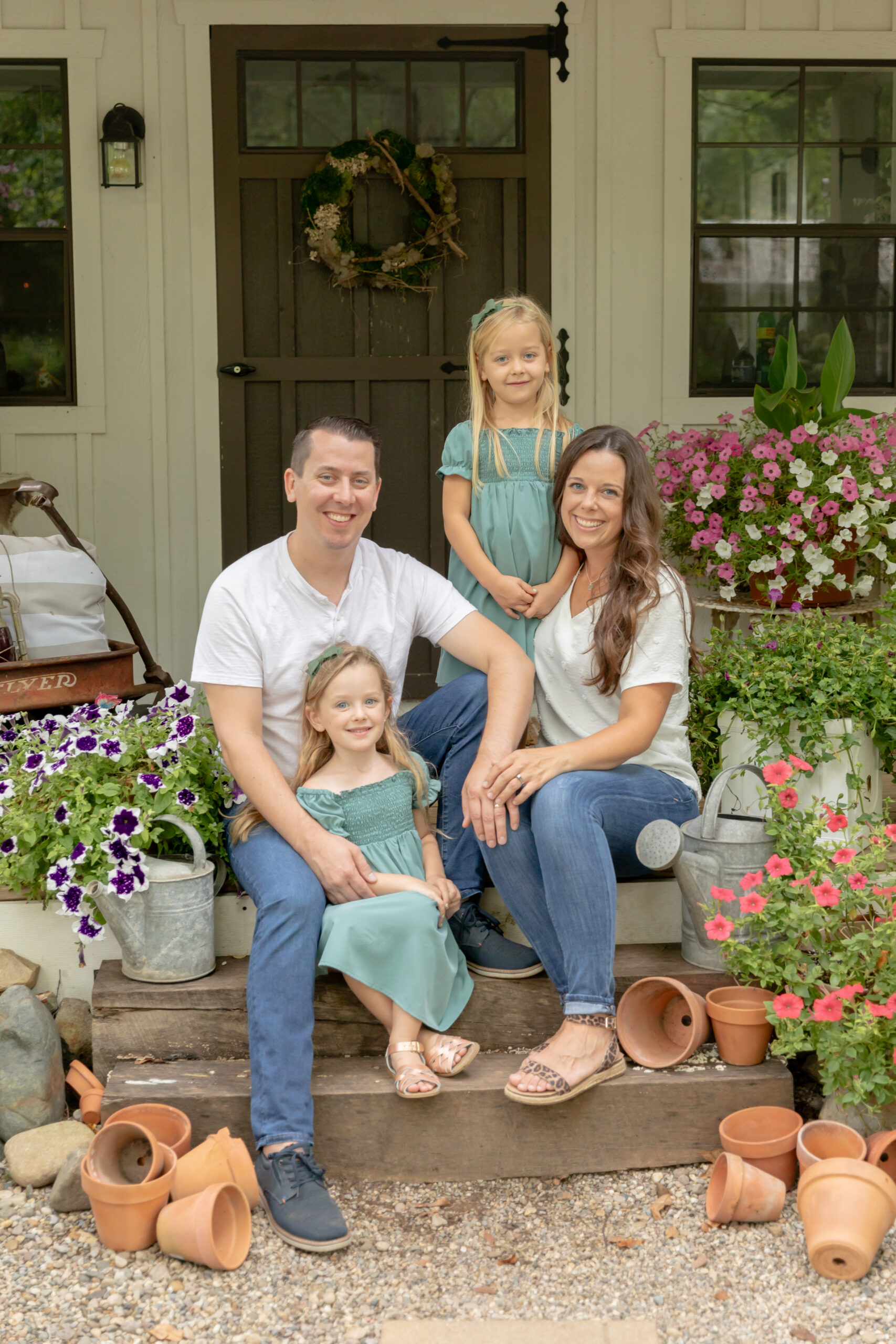 Family of four sits on the steps of a well manicured she shed at Rustic Wild Arrow in Brooklyn, Michigan