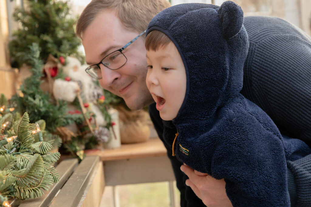 A father and his young son look at a christmas display together in a greenhouse