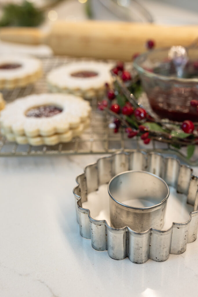 linzer cookie cutter with linzer cookies and raspberry jam in background