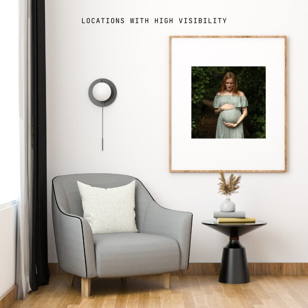 framed print of a pregnant mother in a forest hangs on a wall in a minimalist decorated corner with chair