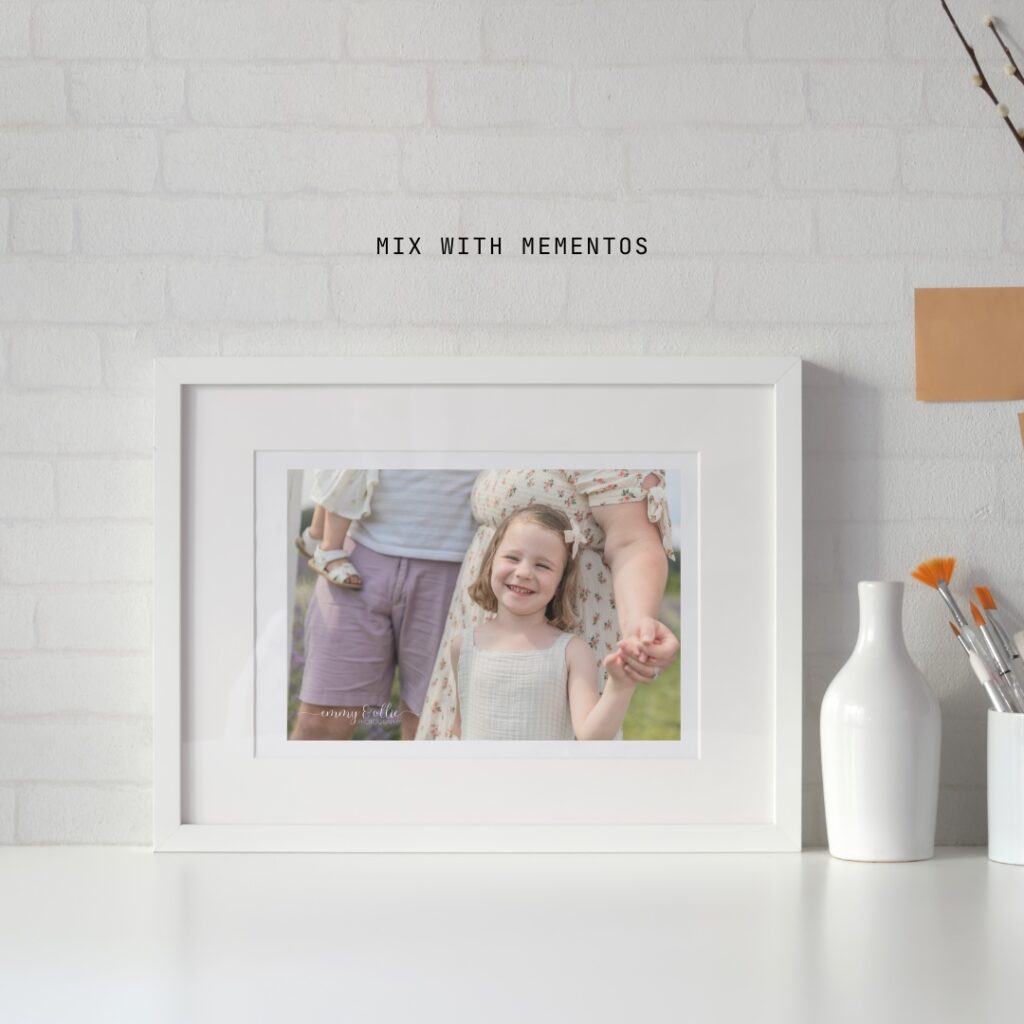 framed photo of young girl laughing sits on a counter with a vase and cup with paintbrushes