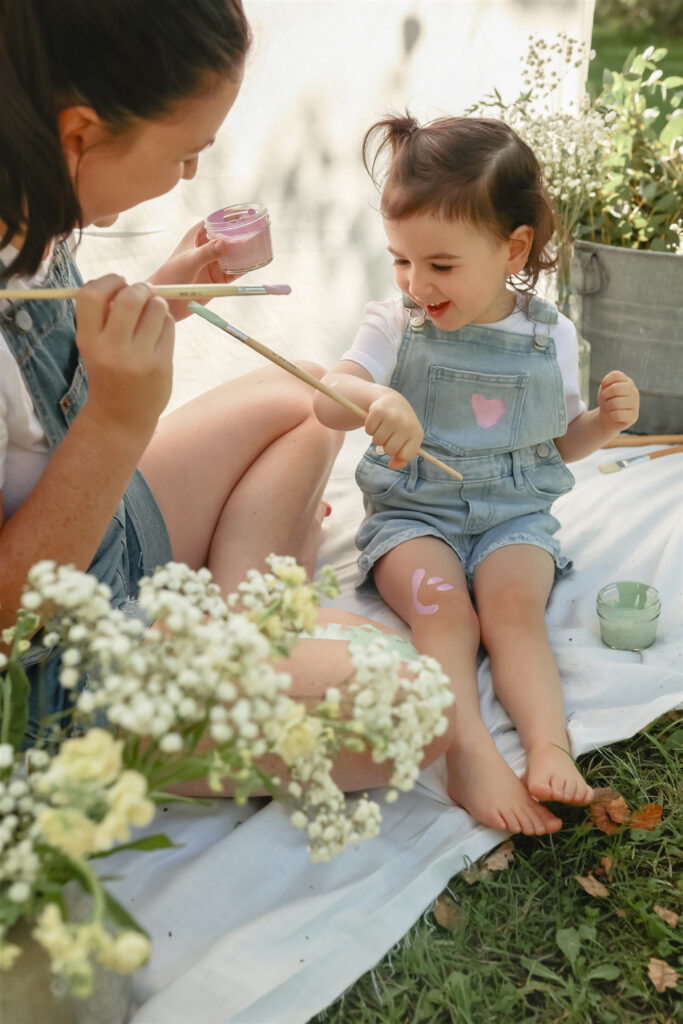 young girl inspects paint on her arm and smiles during a mother daughter paint party photoshoot