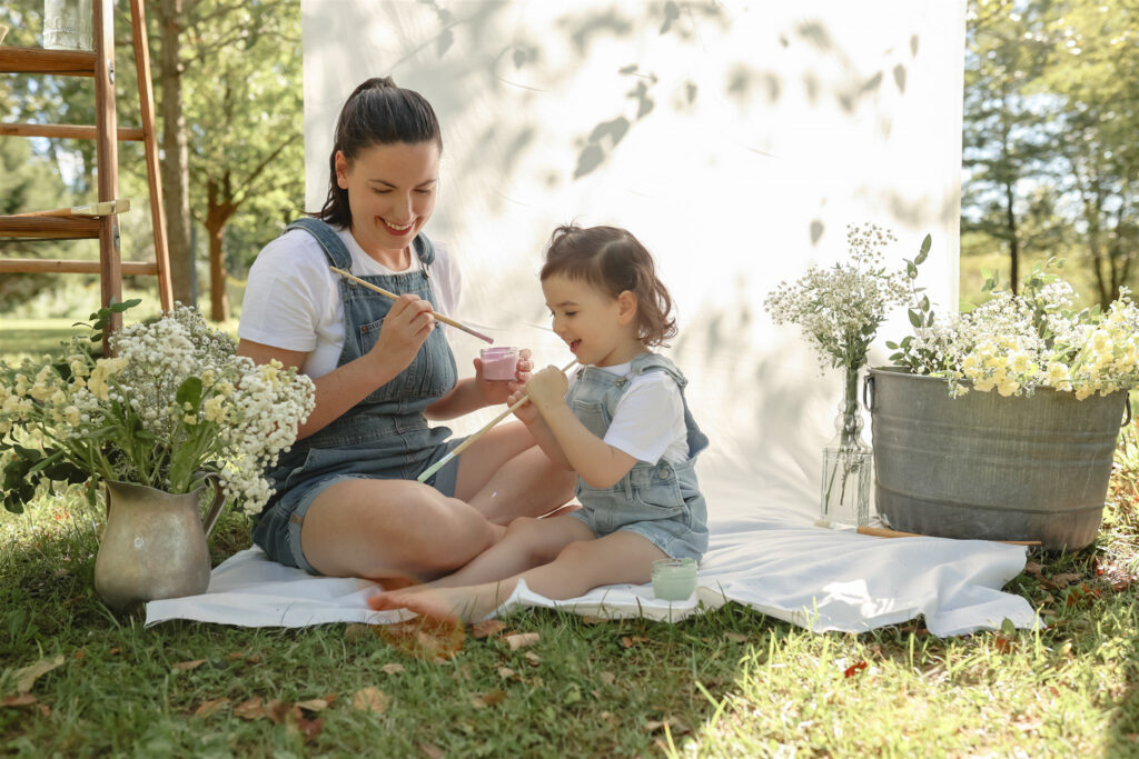 young girl paints her mother's leg during a mother daughter paint party photoshoot