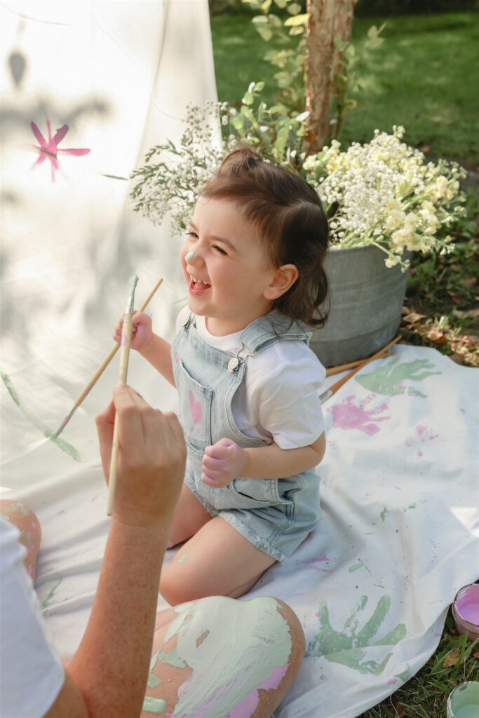 girl laughs after mother painted her nose during mother daughter paint party photoshoot