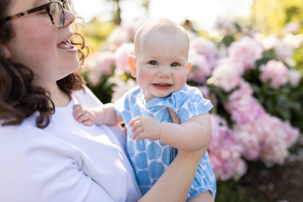 Mother holds baby girl while she smiles in Peony Garden at Nichols Arb in Ann Arbor