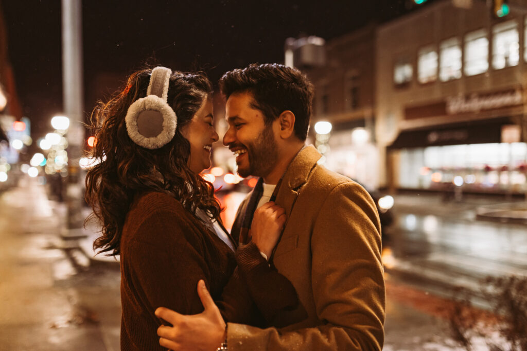 man and woman stand nose to nose and laugh on street corner