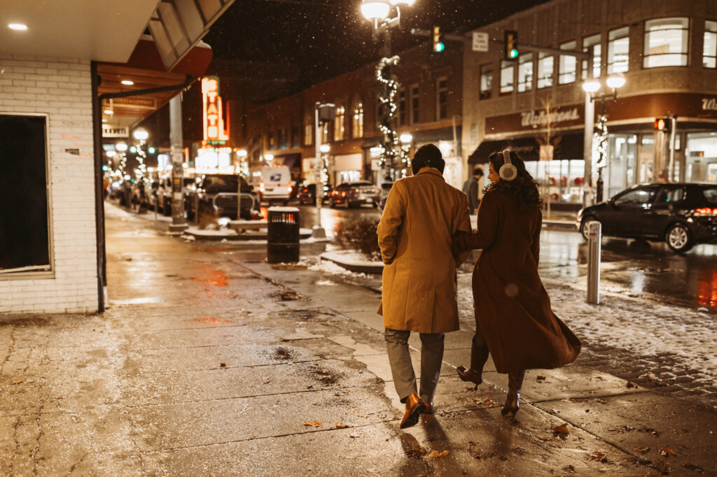man and woman walk arm in arm down state street on a cold winter evening