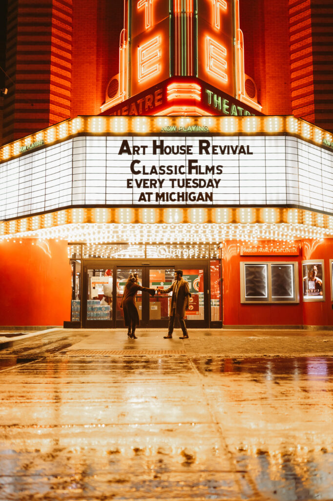 A couple dances below the lit marquee of the state theater