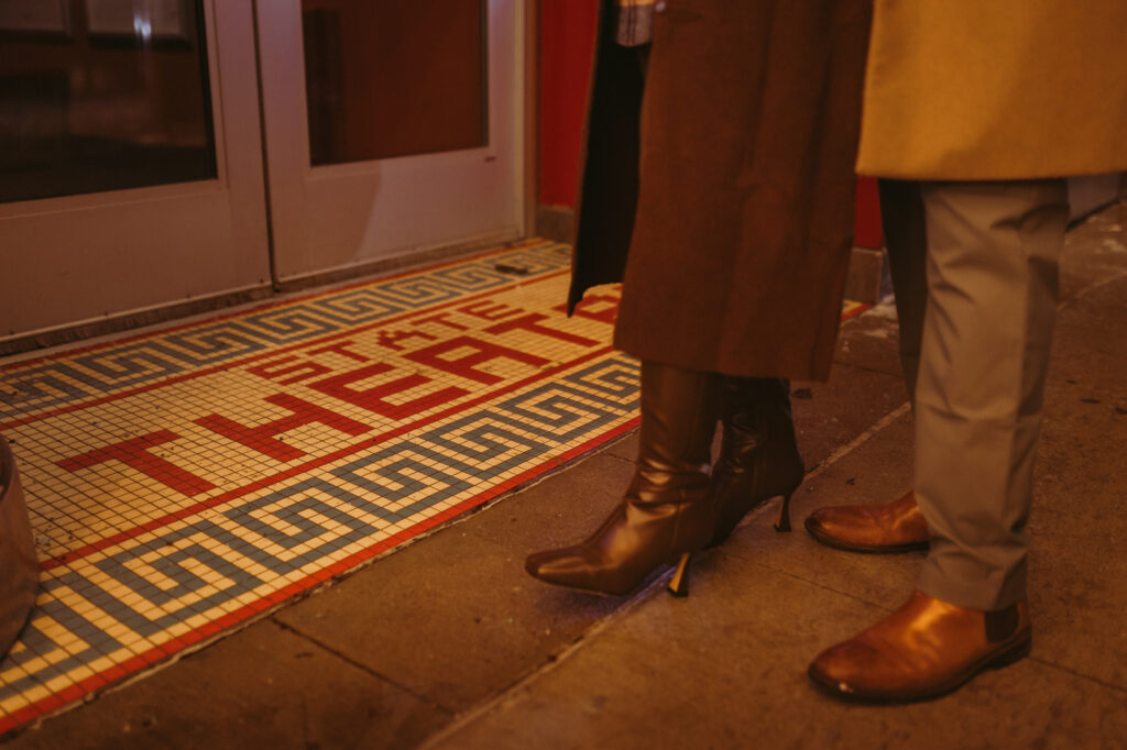 Close up of husband and wife's feet standing near the mosaic at the entrance to the state theater in ann arbor michigan