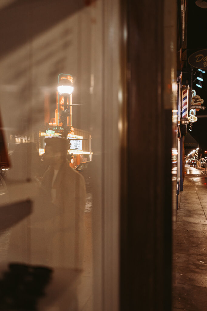 Reflection of a couple kissing in a window with the state theater marquee behind them