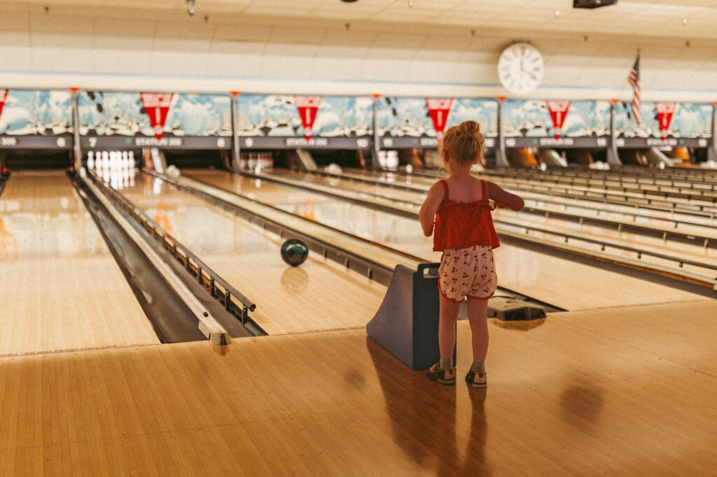 girl stands and watches bowling ball roll down lane at station 300 in saline michigan