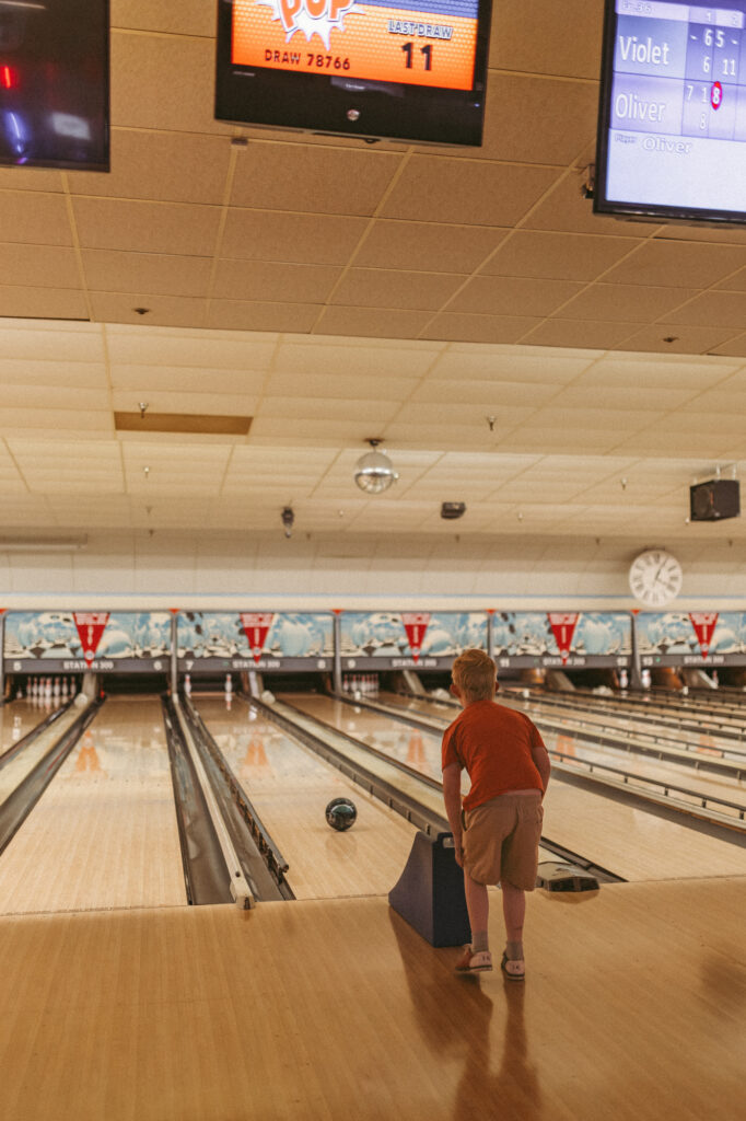 boy waits to see how bowling ball does down the lane