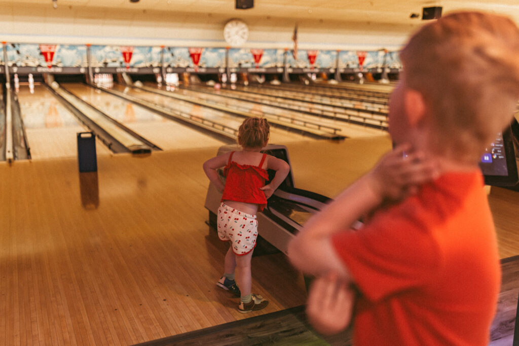 boy and girl wait for bowling ball to return