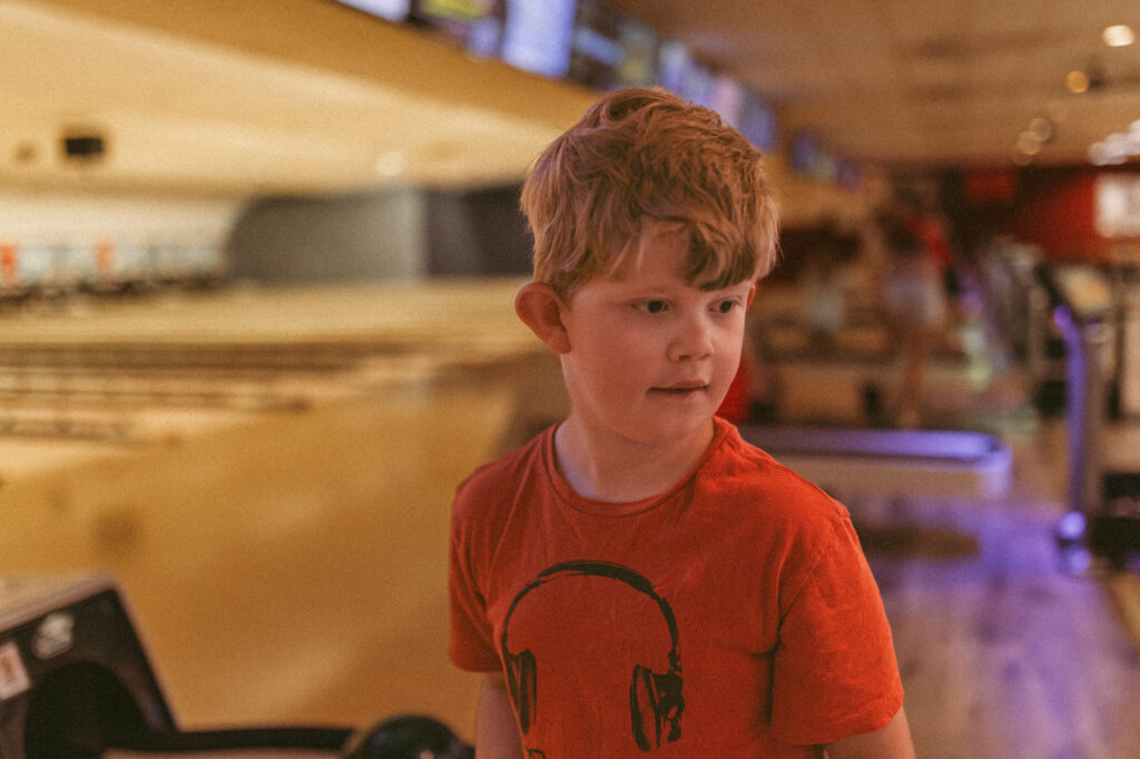 boy stands in bowling alley in saline michigan